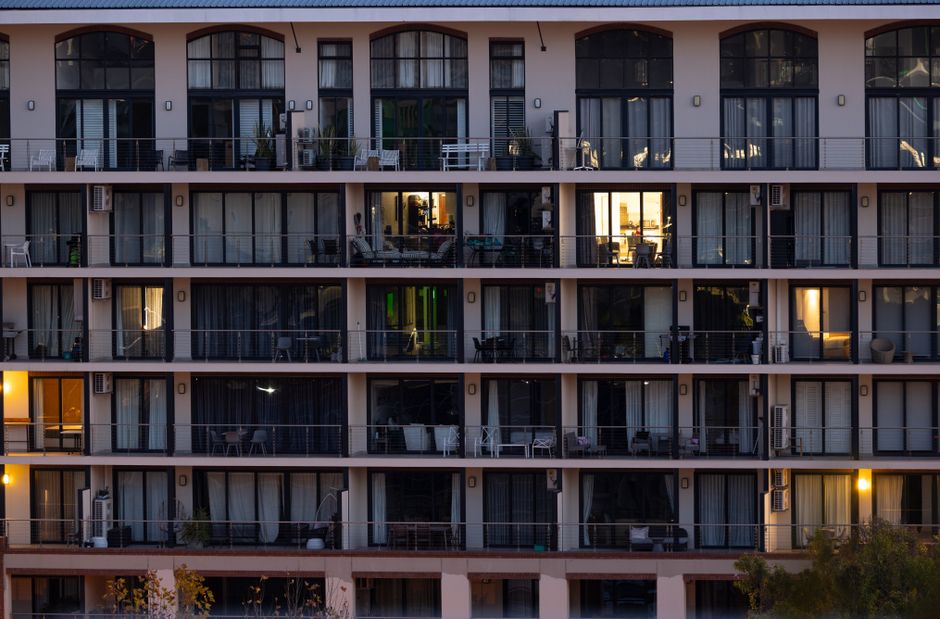 Facade of a modern apartment building at twilight with some rooms illuminated, creating a contrast with the exterior.