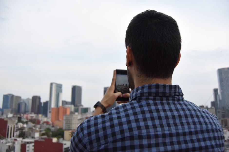 A man photographs the Mexico City skyline using a smartphone. Urban exploration at its finest.