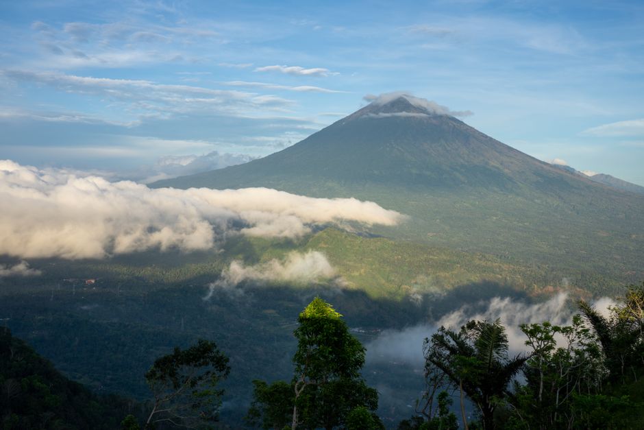 Stunning landscape of Mount Agung with lush greenery and clouds in Bali, Indonesia.