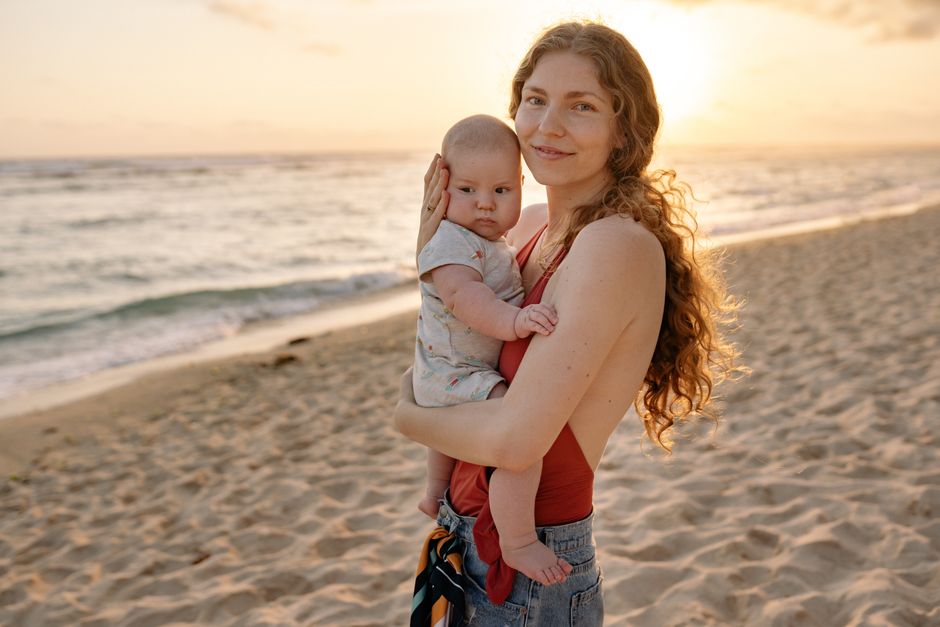 Mother and baby at the beach during sunset. Warm and serene moment captured outdoors.