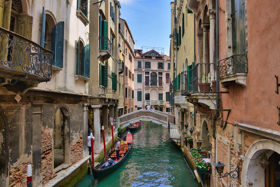A picturesque canal in Venice, Italy, with gondolas and historic architecture under a clear blue sky.