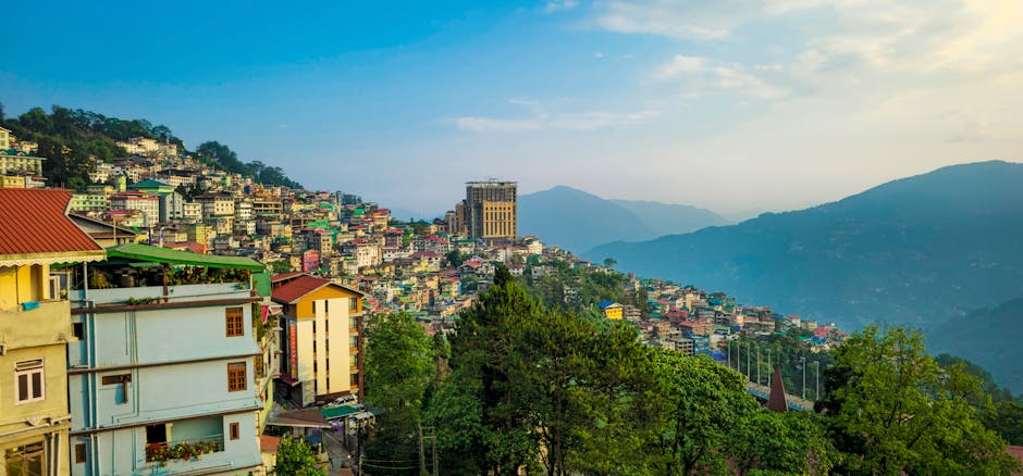 Vibrant view of Gangtok's hillside architecture with lush green surroundings under a clear sky.