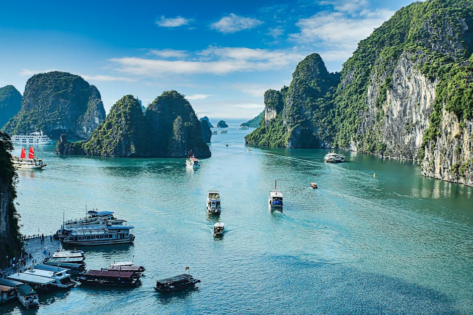 Scenic view of Ha Long Bay with boats navigating through stunning limestone cliffs under a clear blue sky.
