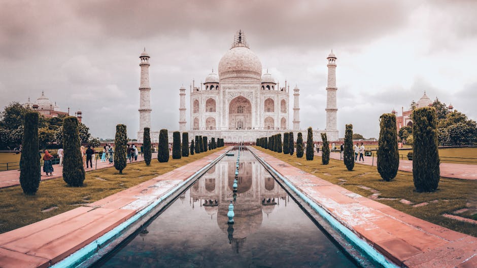 Iconic view of the Taj Mahal with reflection in Agra, India during sunset, highlighting its architectural symmetry.