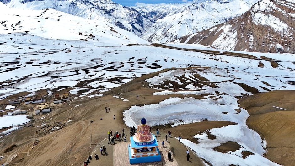 Drone shot of Buddha statue amidst snowcapped mountains in Spiti Valley, HP, India.