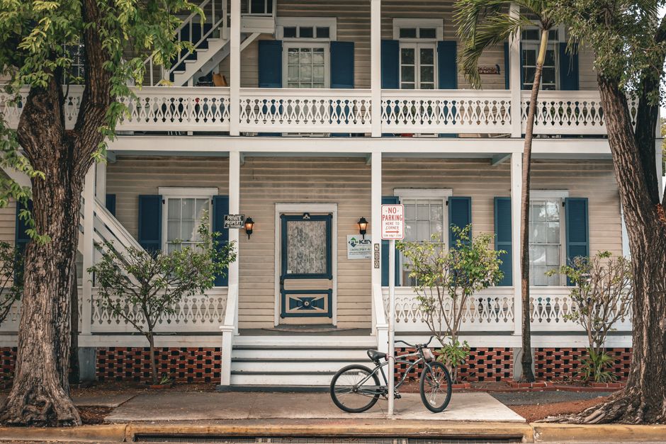 Colonial-style house with blue shutters and a bicycle parked out front, capturing vintage charm and serenity.