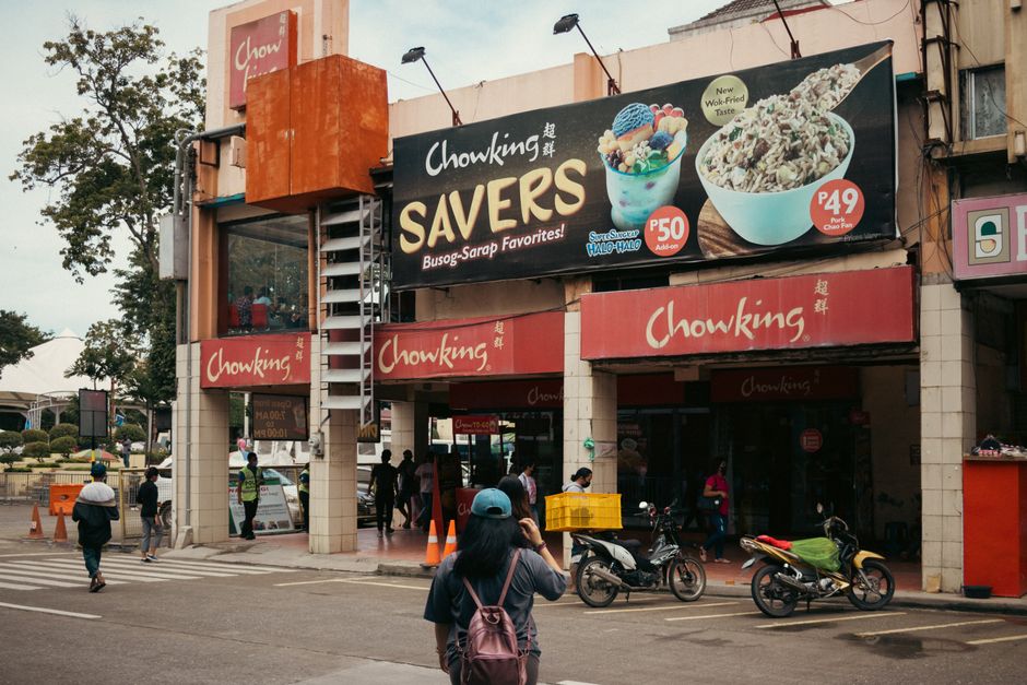 Urban street view with people and motorbikes outside Chowking in Davao City, Philippines.