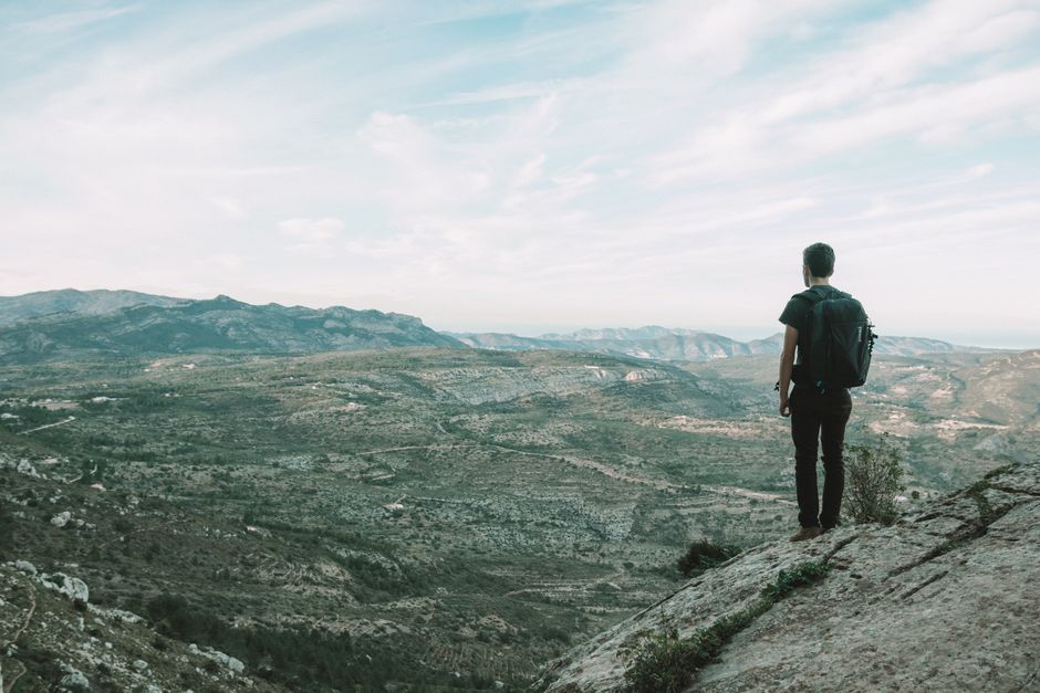 A hiker stands on a rock admiring the vast mountainous landscape in Spain.