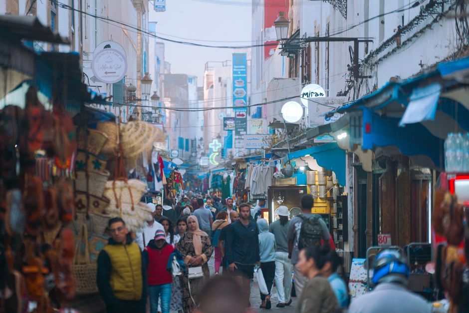 Lively street scene in Essaouira Medina, capturing locals shopping and vibrant souk culture.