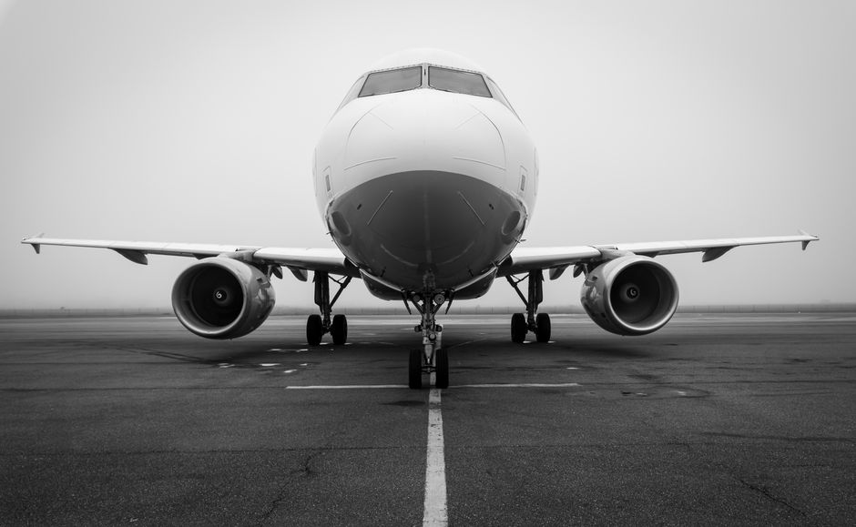 A black and white photo of an airplane on a foggy runway, captured head-on. Ideal for aviation themes.