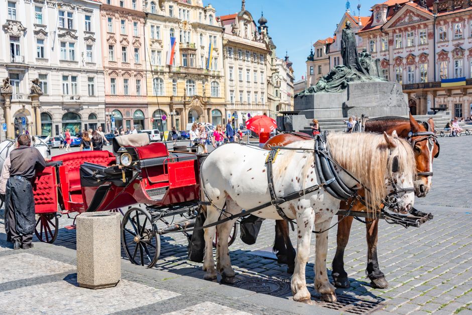 Historic charm with horse-drawn carriage and vibrant architecture in Old Town Square, Prague.