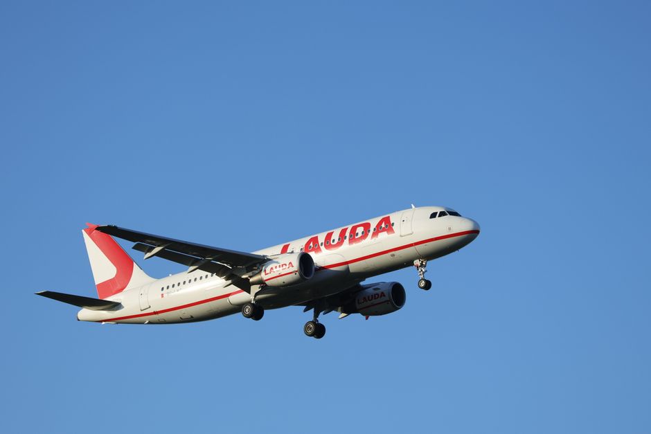 A Lauda Airline Airbus A320 airplane flying against a clear blue sky, showcasing aircraft travel.