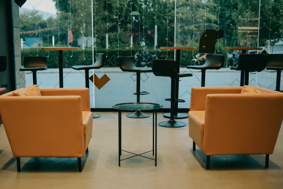 Modern cafe interior with orange armchairs and glass panels for a relaxed atmosphere.