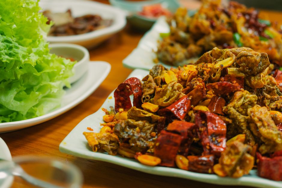 Delicious spicy Asian dish featuring crispy pork, red peppers, and fresh lettuce on a restaurant table.