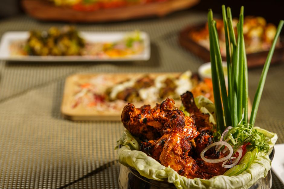 A close-up of spicy grilled tandoori chicken served with fresh garnishes.