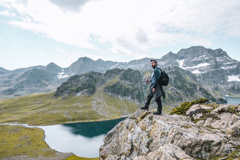 A lone hiker standing on a rocky peak, overlooking a breathtaking mountain landscape.