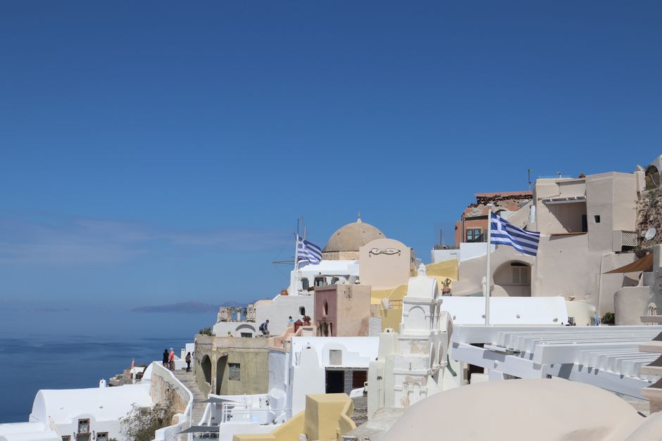 Breathtaking Santorini village of Oia with iconic Greek architecture and flags.