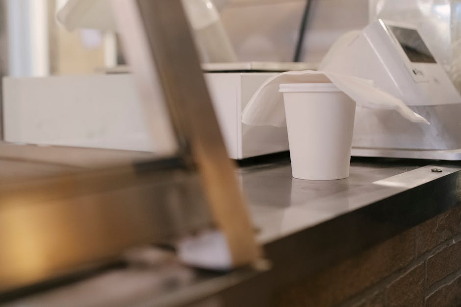 Disposable cup ready for pickup at a cafe counter, conveying a busy coffee shop vibe.