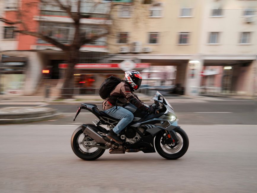 Motorcyclist in motion on a city street in Lisbon, Portugal, showcasing urban lifestyle.