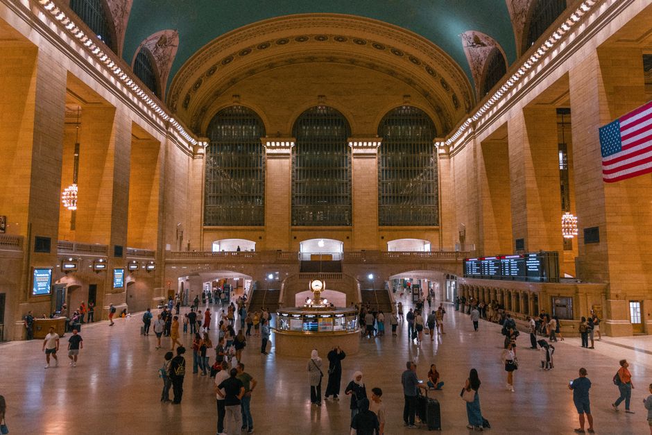 Bustling interior view of New York's Grand Central Terminal with visitors under iconic architecture.