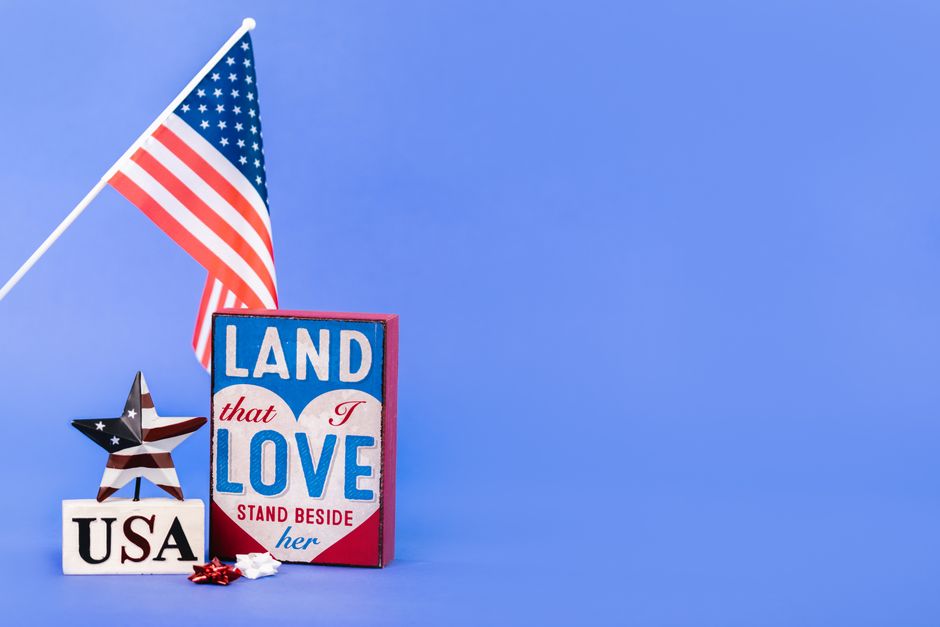 American flag with 'Land that I Love' sign against a blue background. Perfect for patriotic themes.
