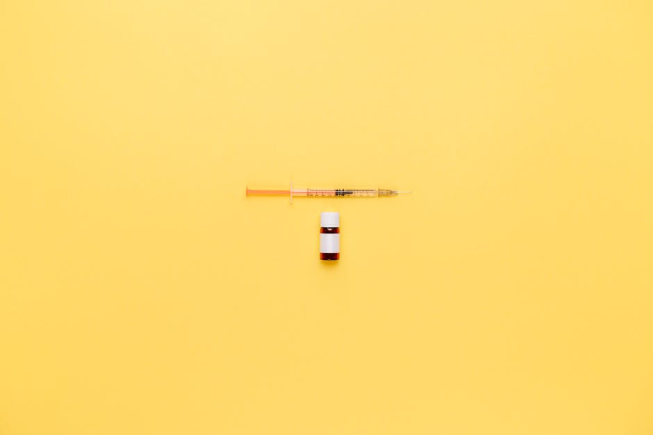 Minimalist image of a syringe and vaccine vial on a vibrant yellow background.