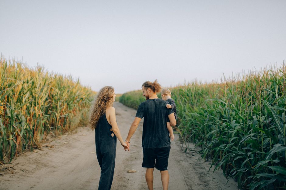 A family strolls along a path in a cornfield, capturing moments of love and togetherness.