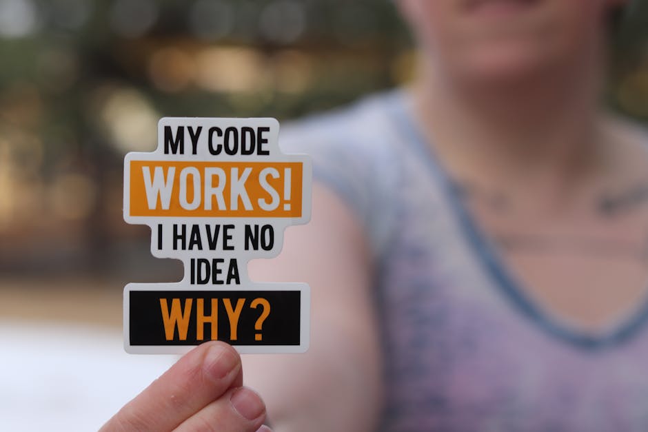 A close-up of a hand holding a humorous programming sticker perfect for tech enthusiasts.