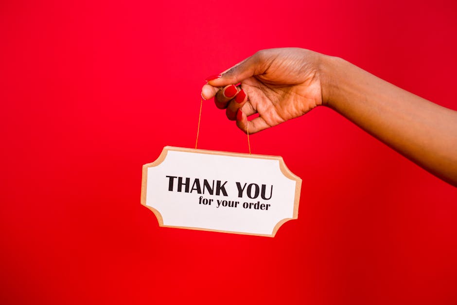 A person holding a thank you sign against a vibrant red background.